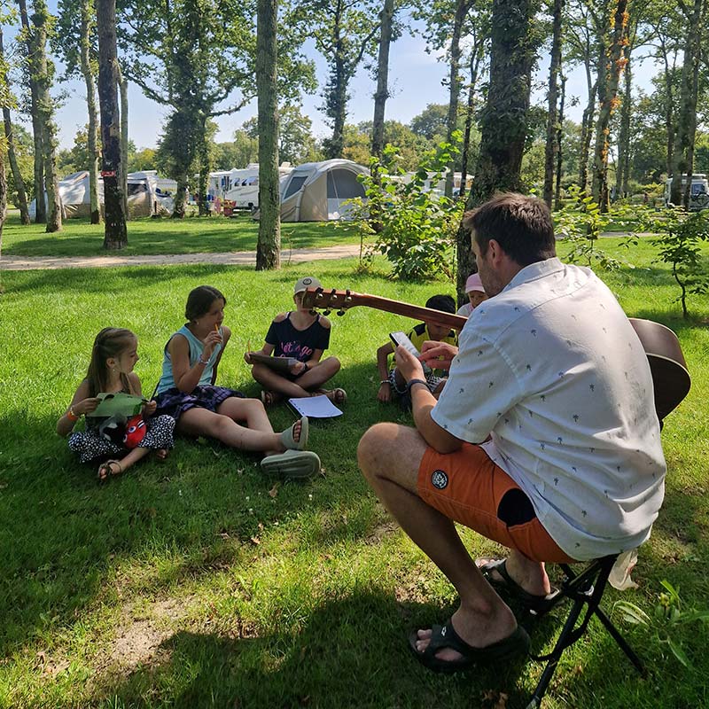 Animateur jouant de la guitare pour les enfants au camping en Bretagne sud