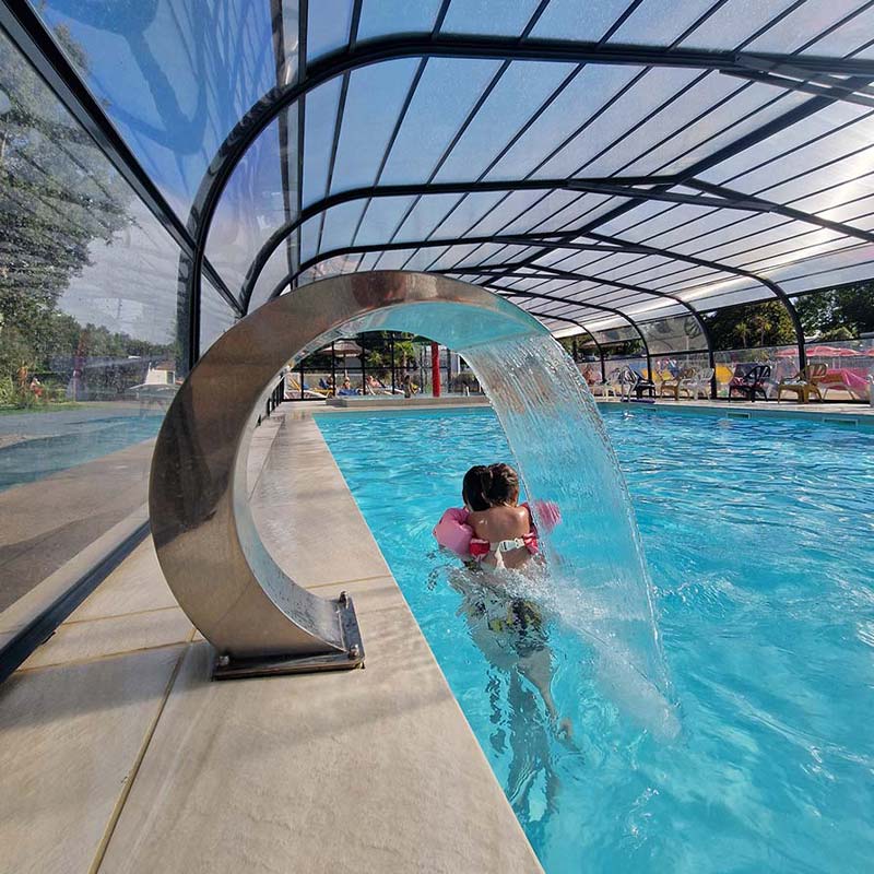 Enfant sous un jet d'eau dans la piscine couverte du camping à Saint-André-des-Eaux en Bretagne sud