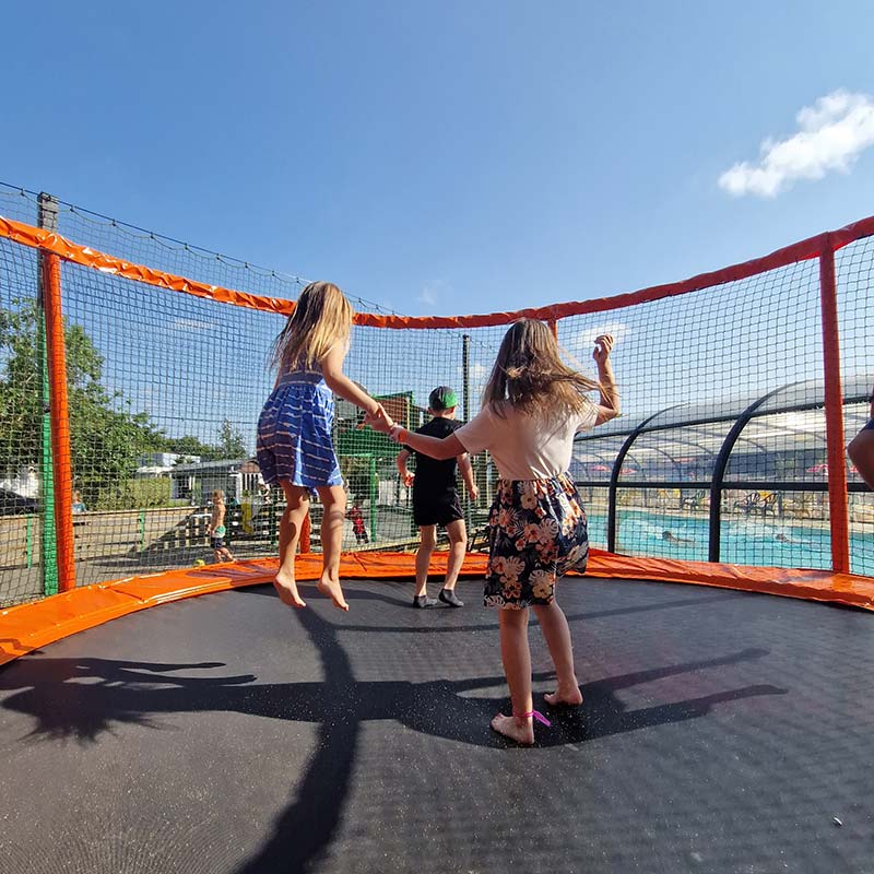 Fillettes jouant sur un trampoline près de l'espace aquatique du camping près de la Baule