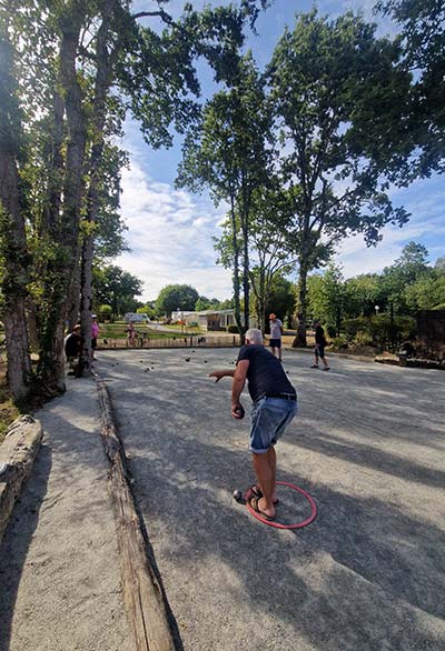 Campeur jouant à la pétanque sur le boulodrome du camping près de la Baule